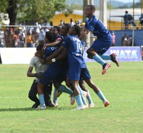 The Manning’s School goal keeper Mikhail Romans (left) is swarmed by his teammates after his heroics help them defeat Dinthill Technical High School in an ISSA daCosta Cup semi-final penalty shootout at the STETHS Sports Complex in 2024.