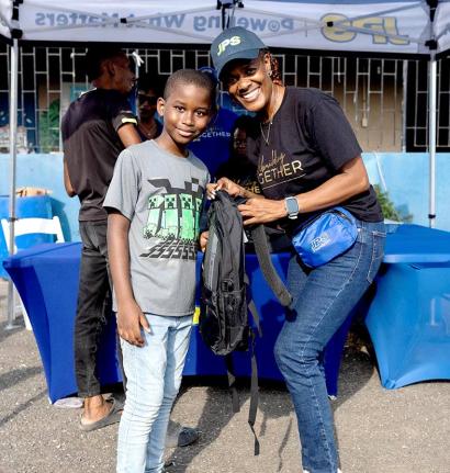 Suzanne Brown (right), administrative assistant, system operations, Jamaica Public Service, presents Ricardo Clarke with a new backpack during a community back-to-school treat at Waterhouse in Kingston on August 30.
