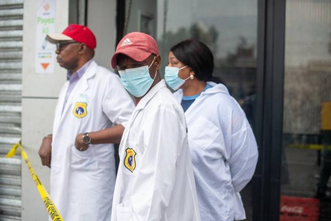 
Forensic officials stand outside a party hall in the aftermath of a fire that broke out in the building hosting a wedding party in Lingwala, Congo, Saturday.