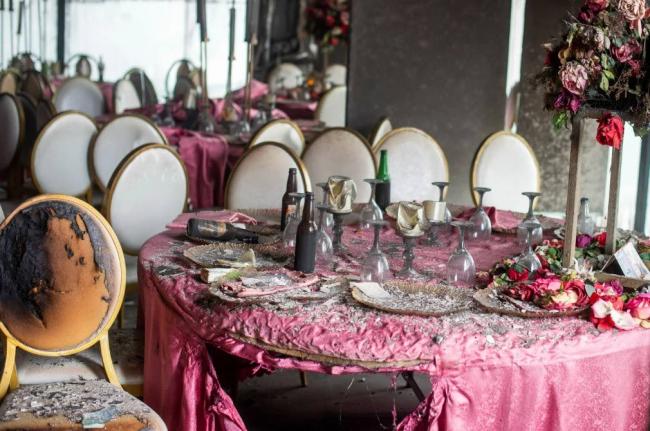 Tablescapes are covered in ash and debris in the aftermath of a fire that broke out in a building hosting a wedding party in Lingwala, Congo, Saturday, September 5, 2026. (AP Photo/Guylain Kipoke) 