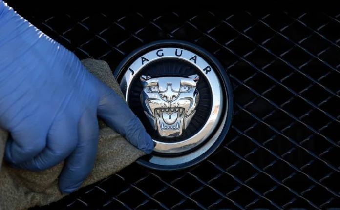 A worker polishes a Jaguar logo on a car at a Jaguar dealer in London, Wednesday, September 28, 2016. 