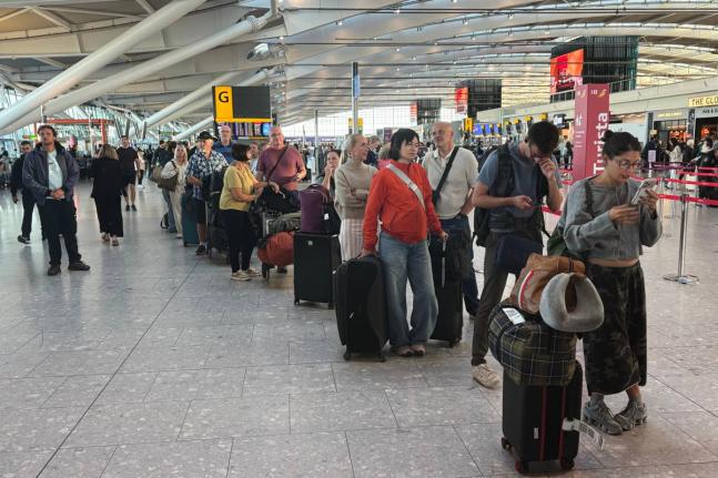 Passengers wait in line at Heathrow Airport in London, during an air traffic control problem that disrupted travel across Britain. (Jonathan Brady/PA via AP)