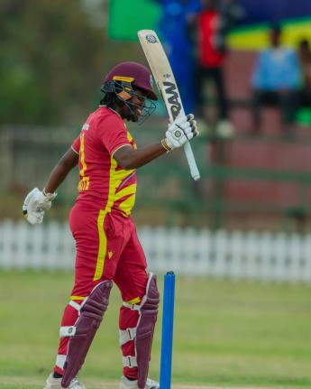 Eboni Brathwaite raises her bat in celebration of scoring a half century against Zimbabwe yesterday.