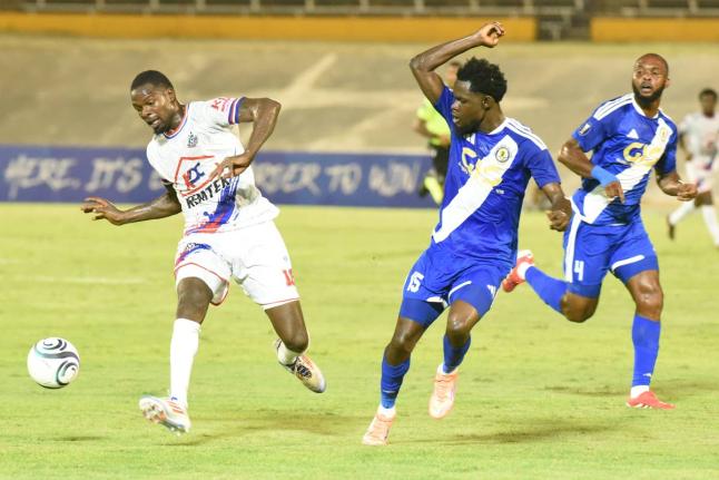 Corey Burke (left) from Portmore United, tries to get the better of Kyle Ming (centre) and Fitzroy Cummings from Mount Pleasant FA during their Concacaf Caribbean Cup match at the National Stadium. 