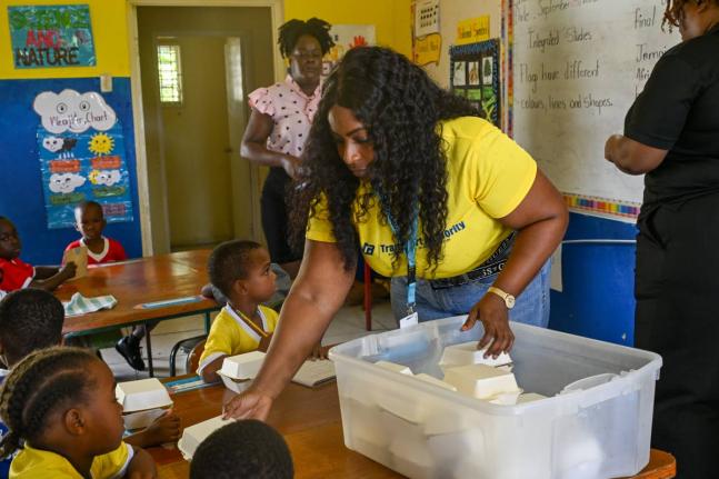 Theresa Garnett, of the Transport Authority of Jamaica’s Customer Service Department, serves breakfast to students at Dalvey Infant School on September 25. 