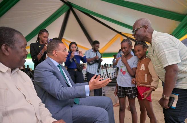Prime Minister Dr Andrew Holness (second left), greets young Tivoli Gardens residents Cathalia Collins (centre) and Mourica Rose, during the Certificate of Possession Handover Ceremony held at the Tivoli Gardens Community Centre in Western Kingston on Wedn