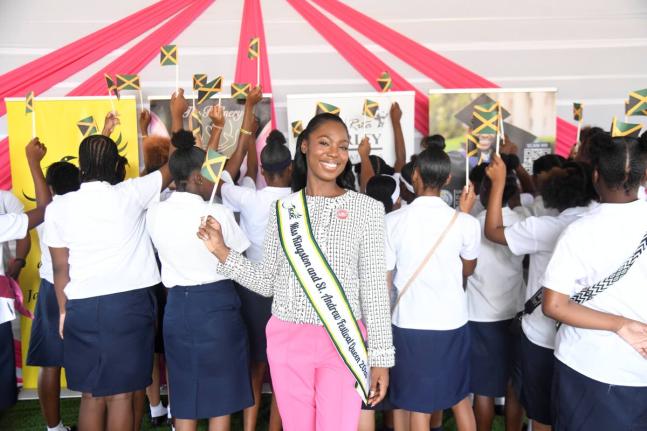Miss Kingston & St Andrew Danielle Cox waves the Jamaican flag with young moms from the Women’s Centre of Jamaica Foundation at the launch ceremony for her project, The Refinery: Becoming, Not Broken, last Friday at the Louise Bennett Garden Theatre in K