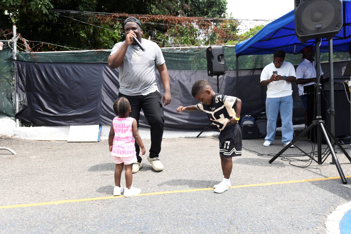 Malik Beckford (centre) dances with siblings one-year-old Sandra Wilkie (left) and five-year-old Shaundre Mattocks at a back-to-school treat hosted by the JP Samuels Foundation at the Grants Pen Peace Park in St Andrew on September 5. 