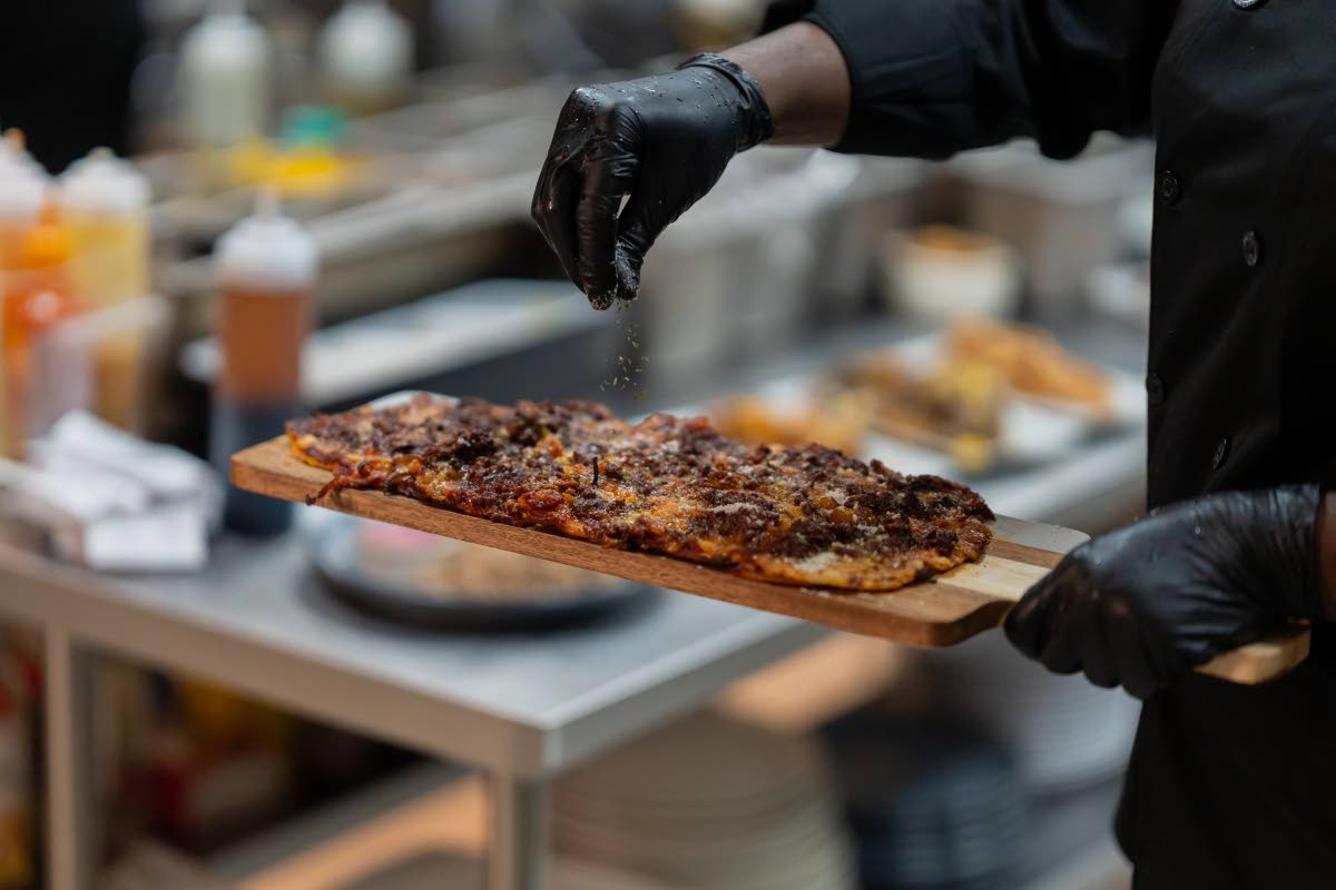 A chef garnishes the cowboy couture BBQ beef flatbread.