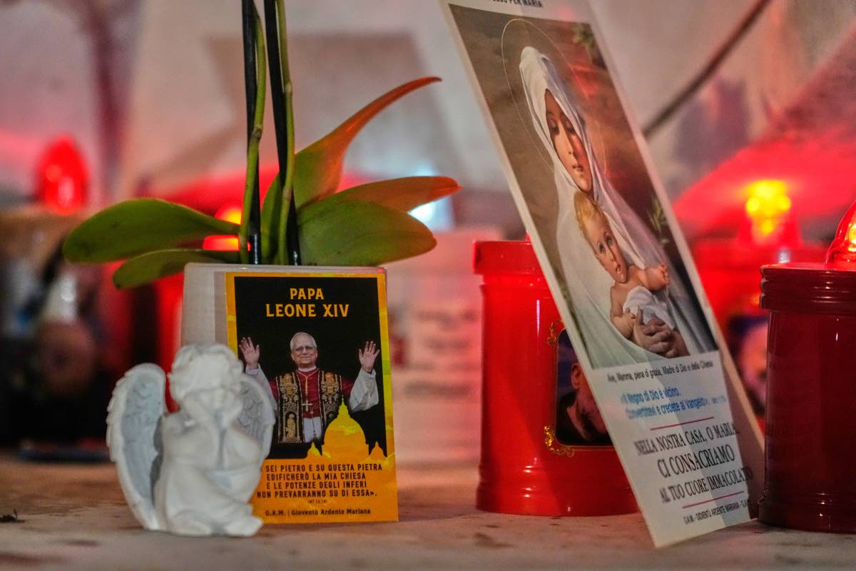 An image of Pope Leo XIV rests at the base of a statue of the late Pope John Paul II outside the Agostino Gemelli Polyclinic, where Leo is hospitalized for surgery to remove a lung nodule, in Rome, Tuesday, Oct. 13, 2026. 