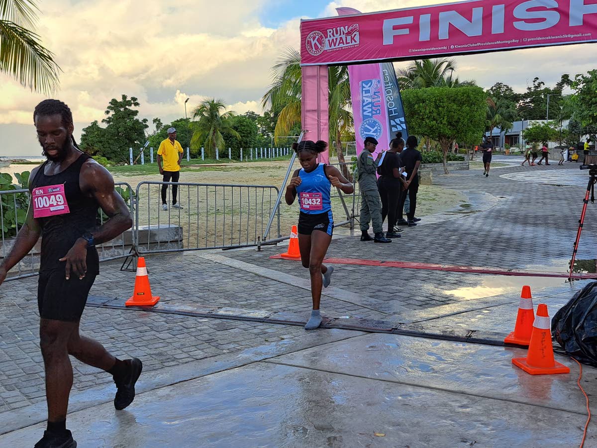 Tracey-Ann Vernon (centre) crosses the line to win the female category.