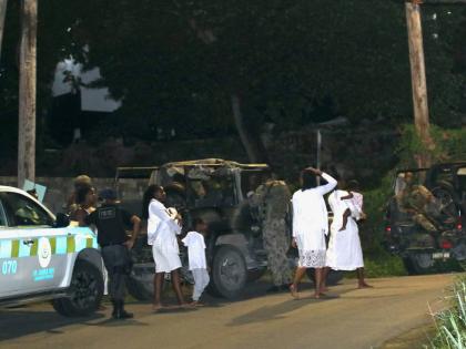 Police and soldiers with members of the Pathways International Kingdom Restoration Ministries outside the Montego Bay-based church, where a deadly service unfolded on October 17, 2021.